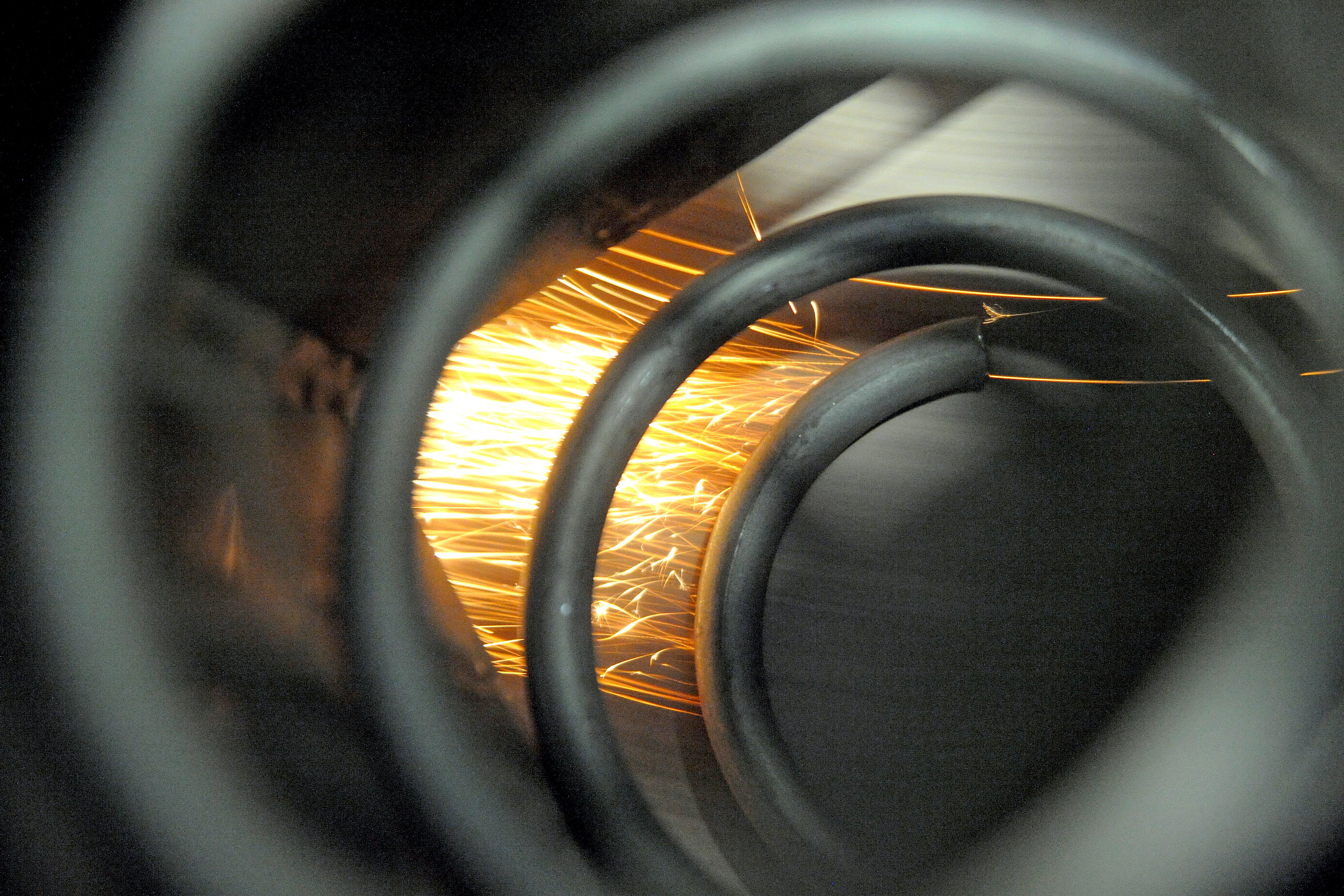 Sparks flying as a metal spring is ground on a machine.