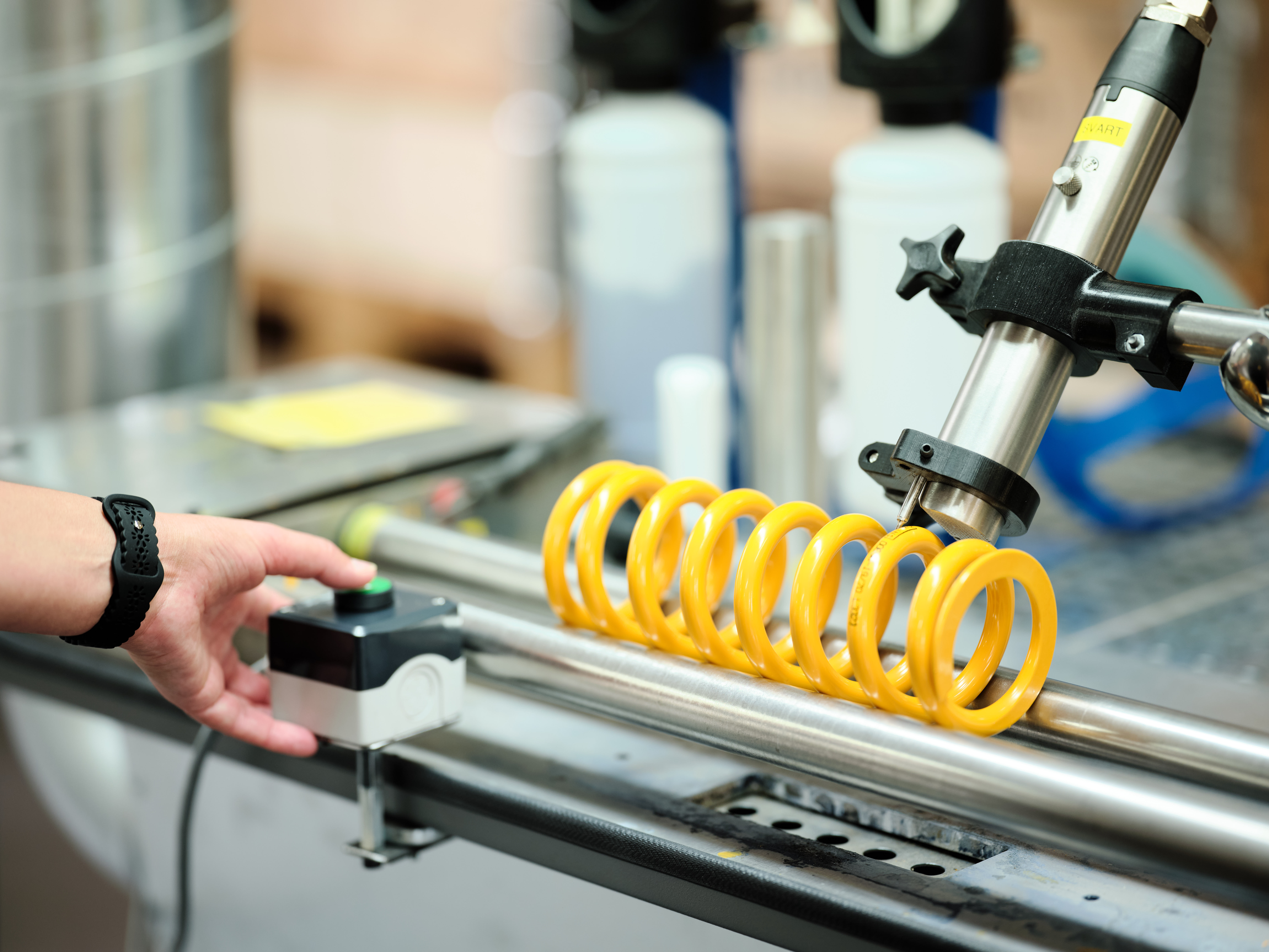 Yellow coil spring on a test bench during inspection.