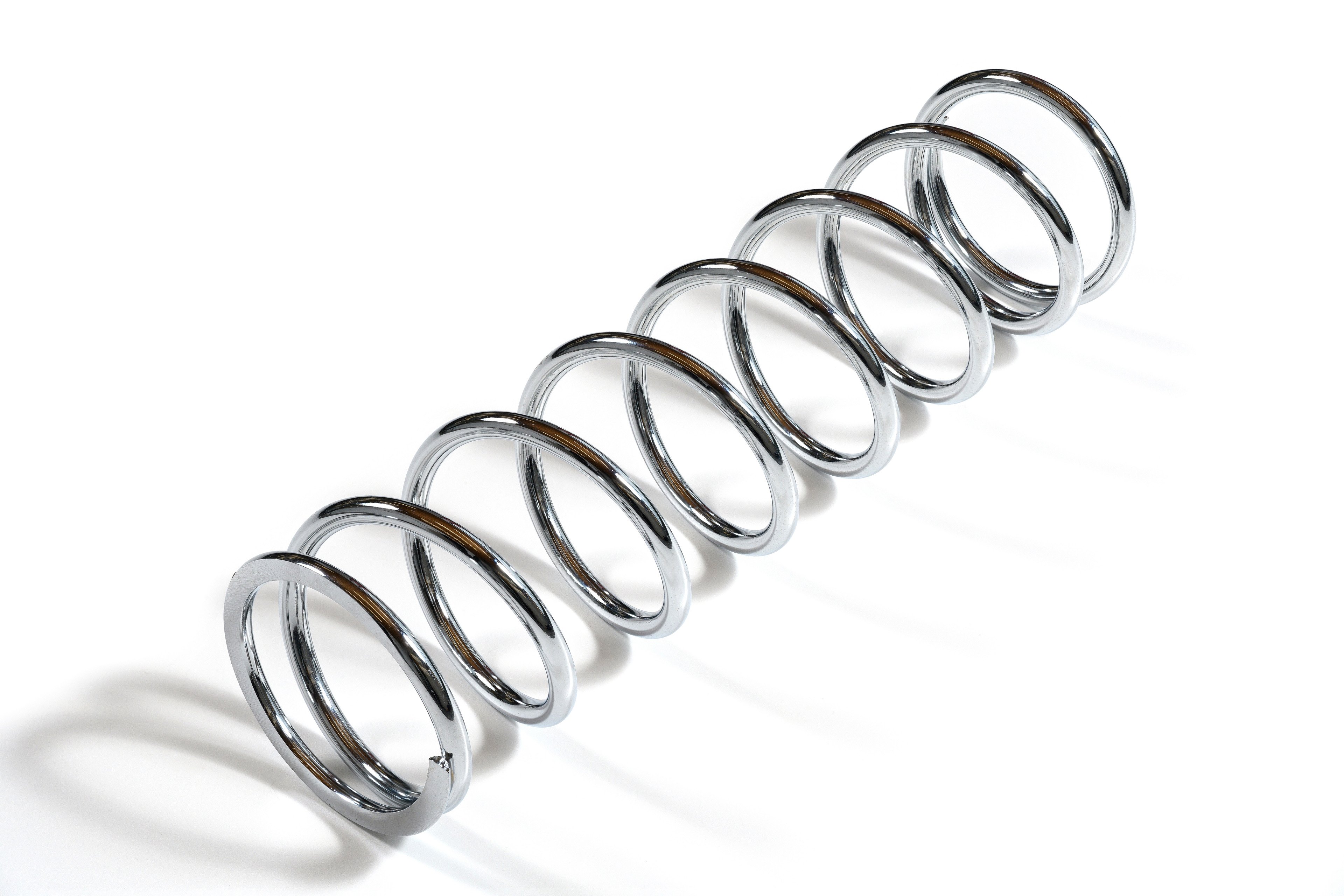 Chrome compression spring on a white background.