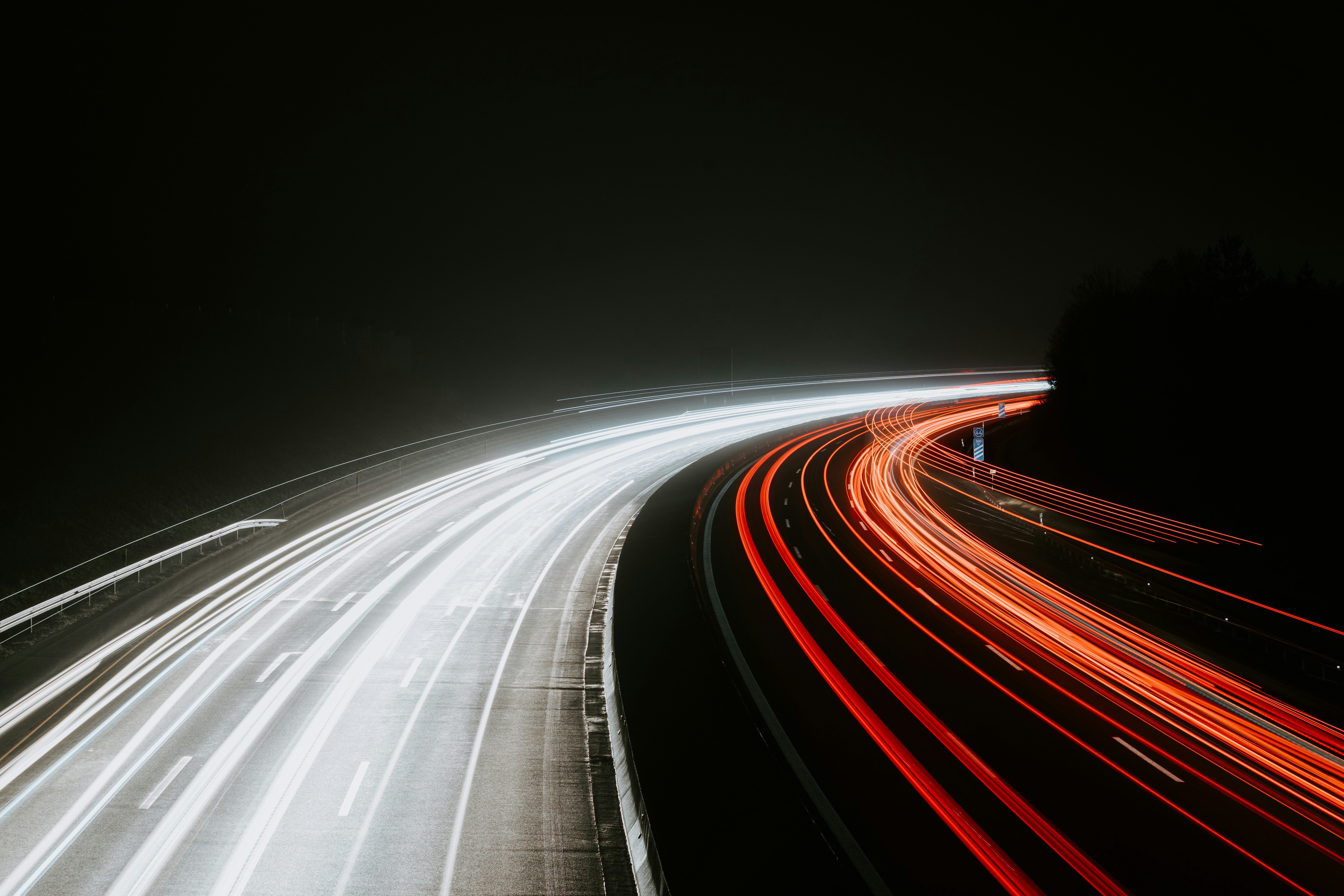 White and red light trails from traffic on a winding motorway at night.