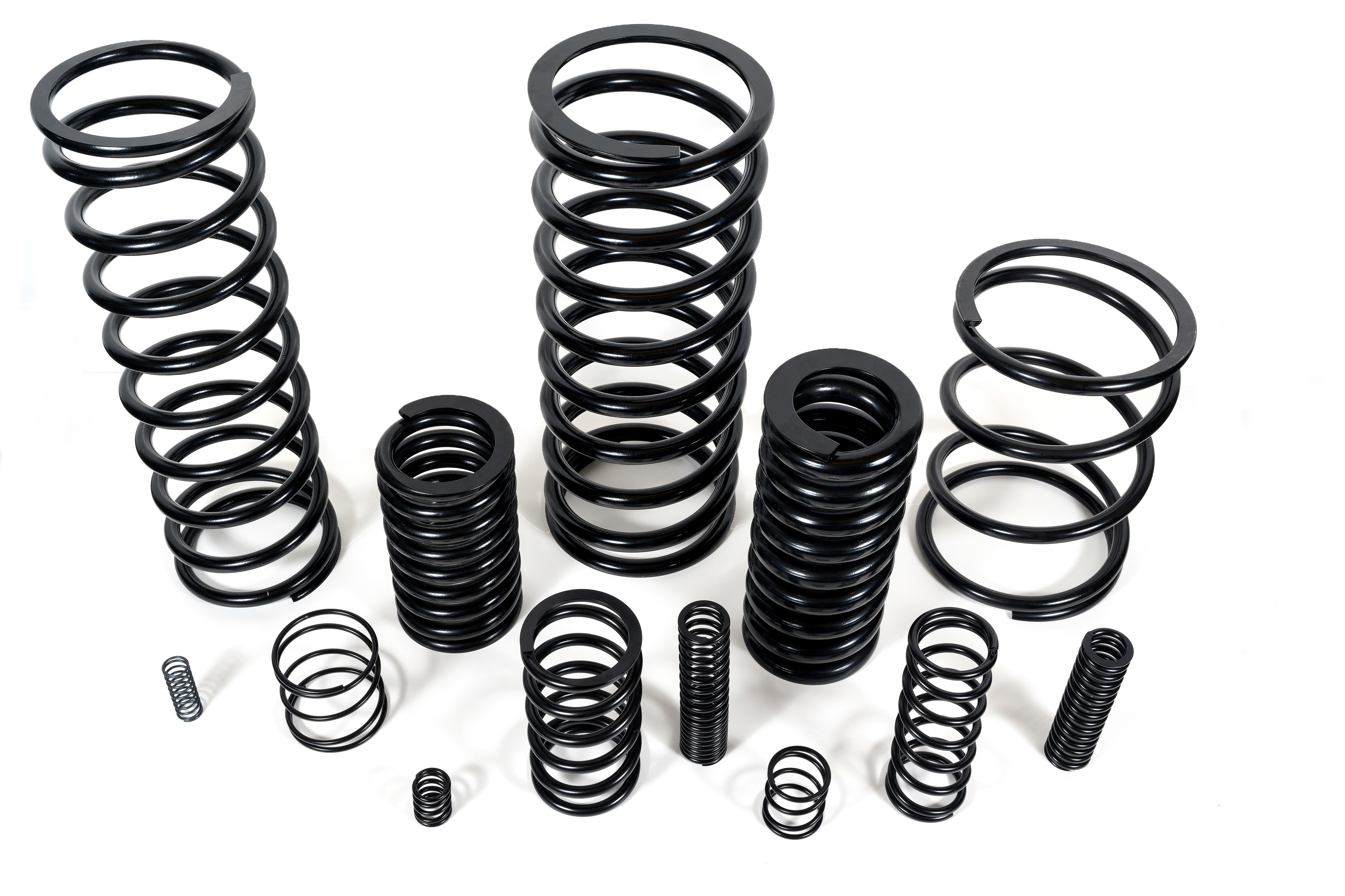 Various black Compression Springs of different sizes and coils are arranged on a white background, showcasing diversity in height and thickness.
