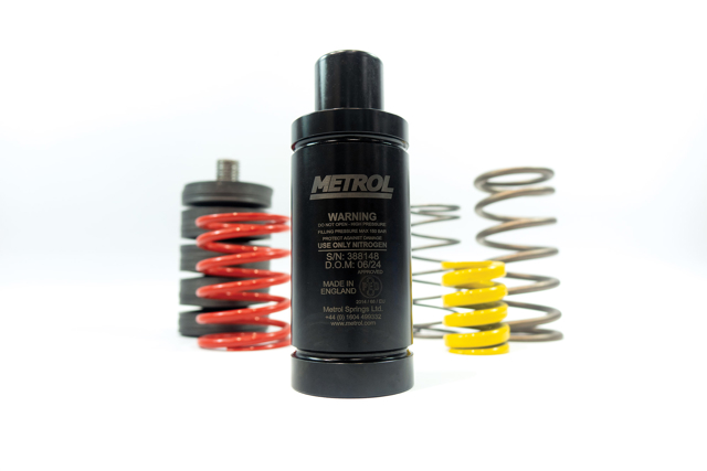 A black nitro spring is centered, featuring cautionary text. Behind, red, yellow, and metal nitro springs are visible.