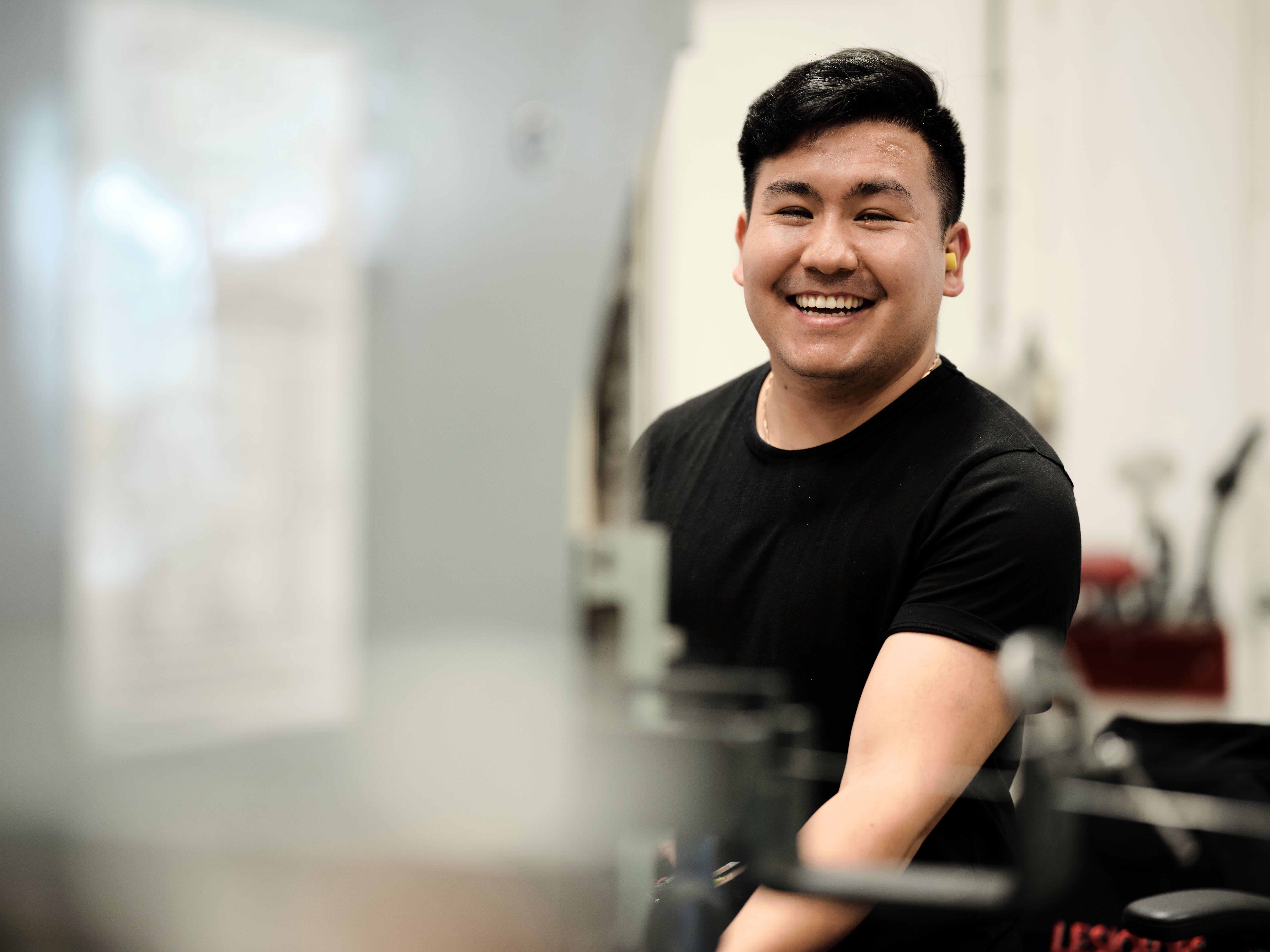 Smiling employee in a factory with machinery in the foreground.