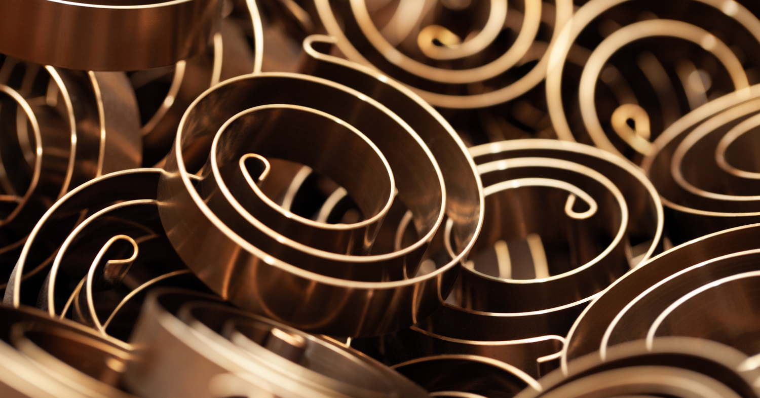 Close-up image of bronze powersprings with circular patterns, creating a spiraling, dynamic texture.