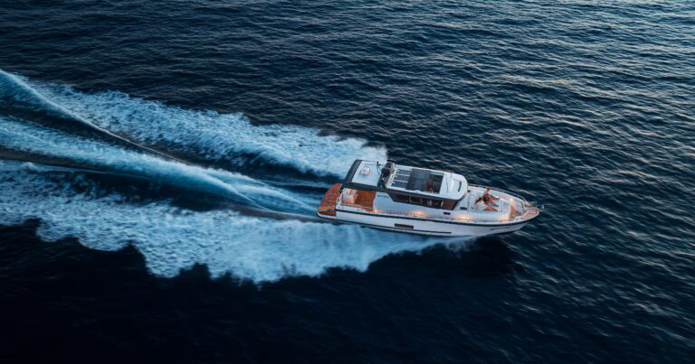 A sleek motorboat speeds across dark blue water, leaving a white foamy trail behind.