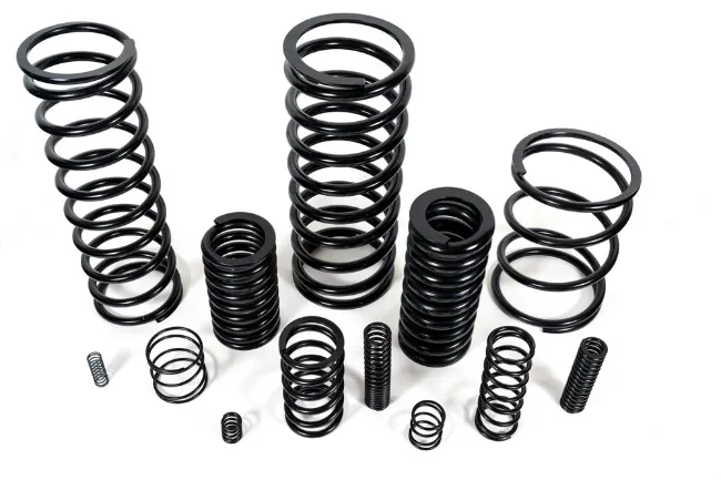 Assorted black compression springs in various sizes arranged on a white background.