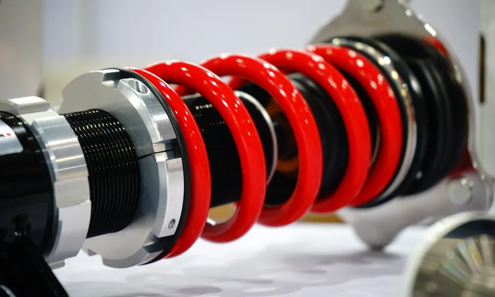 Red coil spring on a automotive coilover suspension unit.
