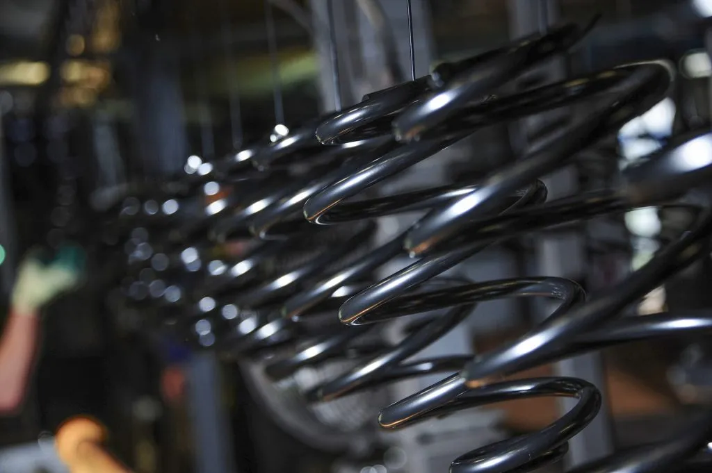 Suspension coil springs on a production line in an industrial manufacturing setting.