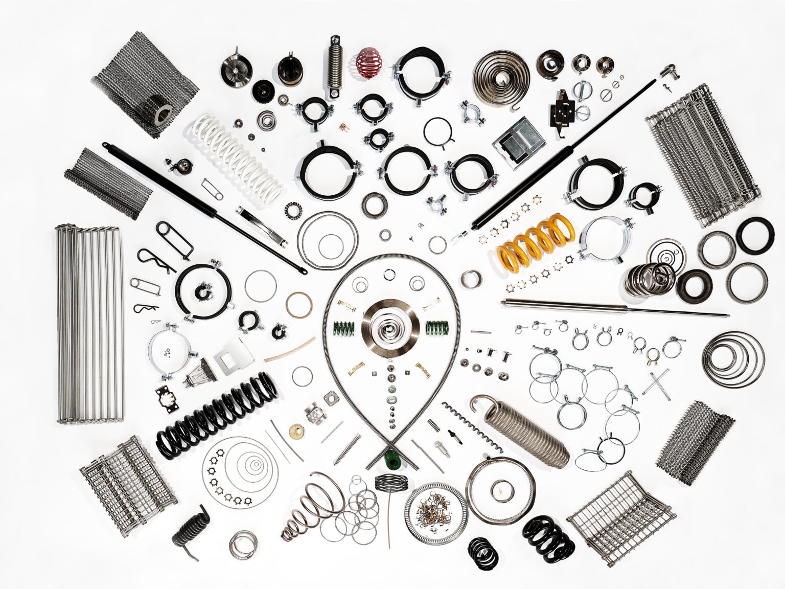 A collection of black and white bearings and mechanical parts arranged in a symmetrical, mandala-like pattern. 