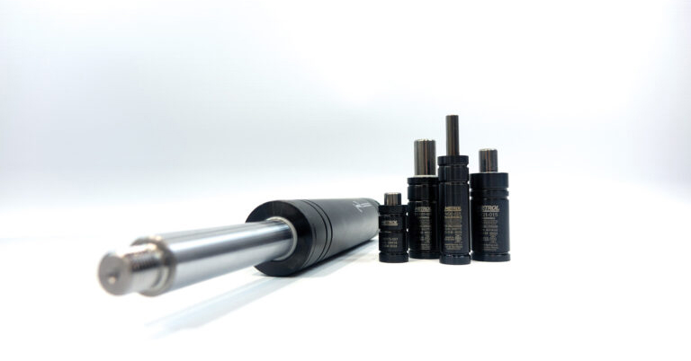 Close-up of a sleek metal cylinder alongside four black industrial components with labels, set against a white background, conveying a modern, technical vibe.