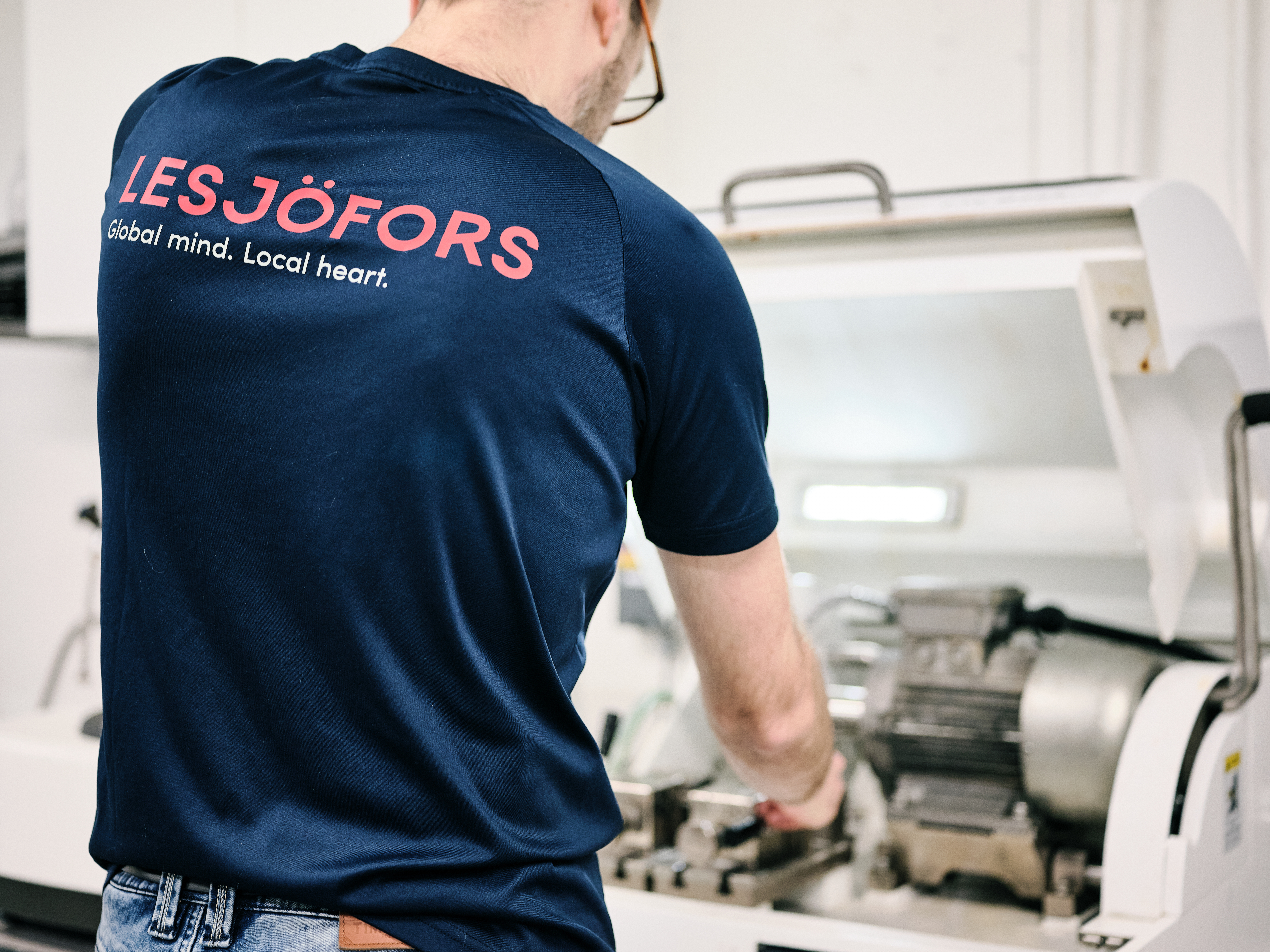Lesjöfors worker seen from behind operating machinery in a workshop.
