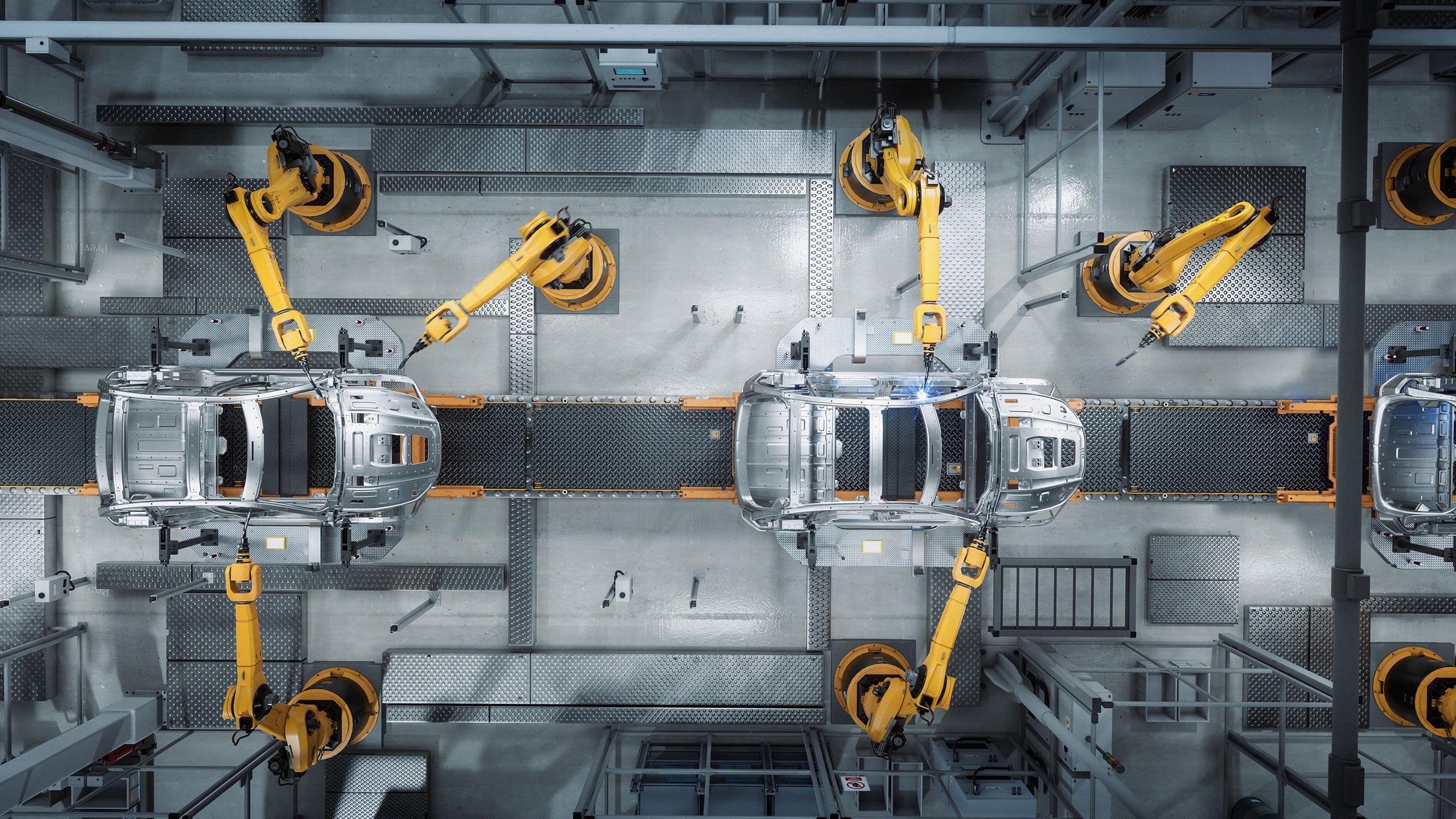 Overhead view of robotic arms assembling car bodies on an automotive assembly line.