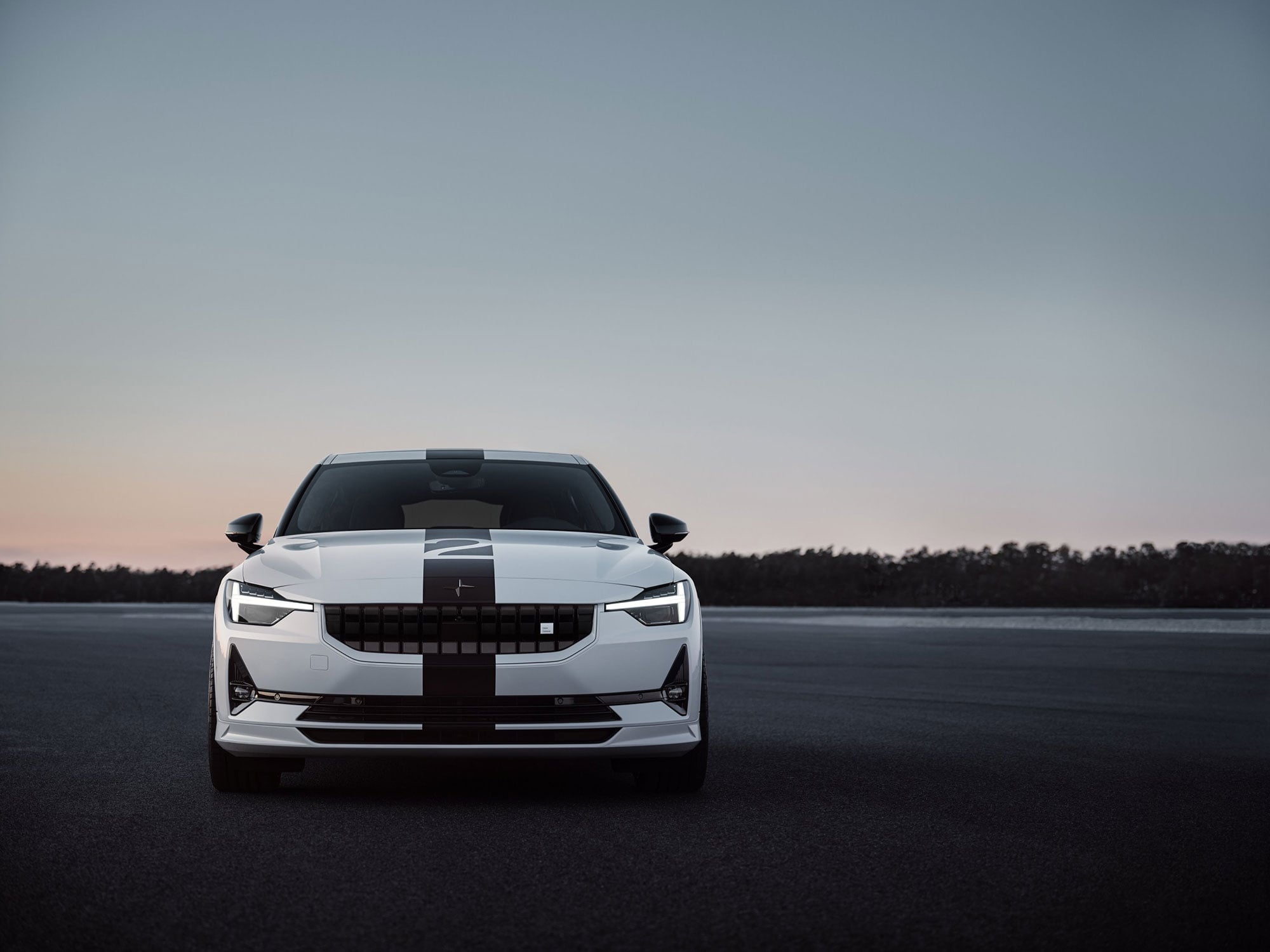 Front view of a white Polestar car with a black center stripe at dusk.
