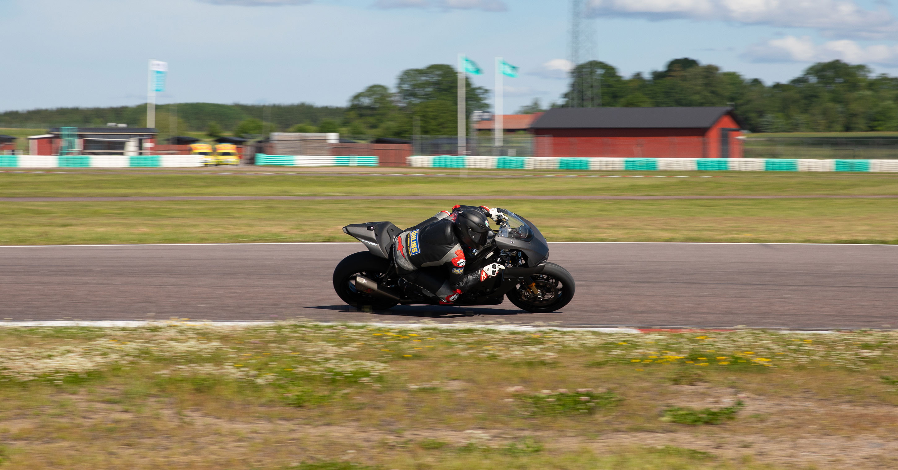 Motorcycle rider leaning into a high-speed corner on a racetrack.