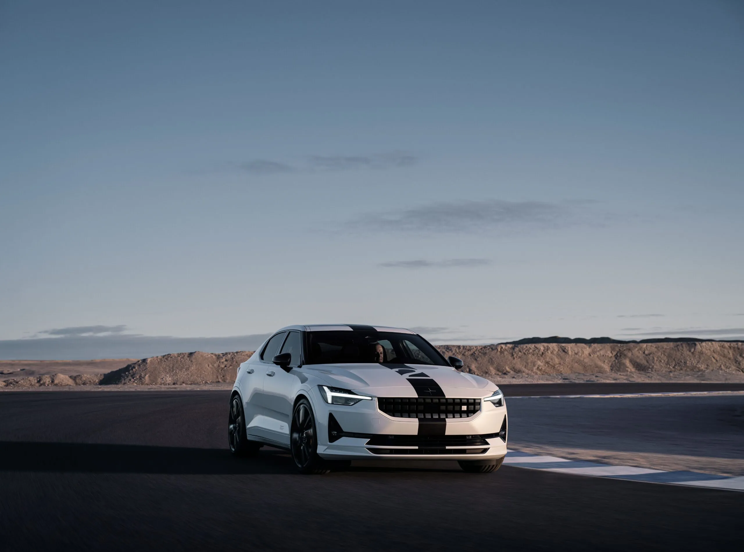 A white Polestar 2 BST edition 270 cruises around a race track, showcasing a real-world application of Lesjöfors suspension springs.