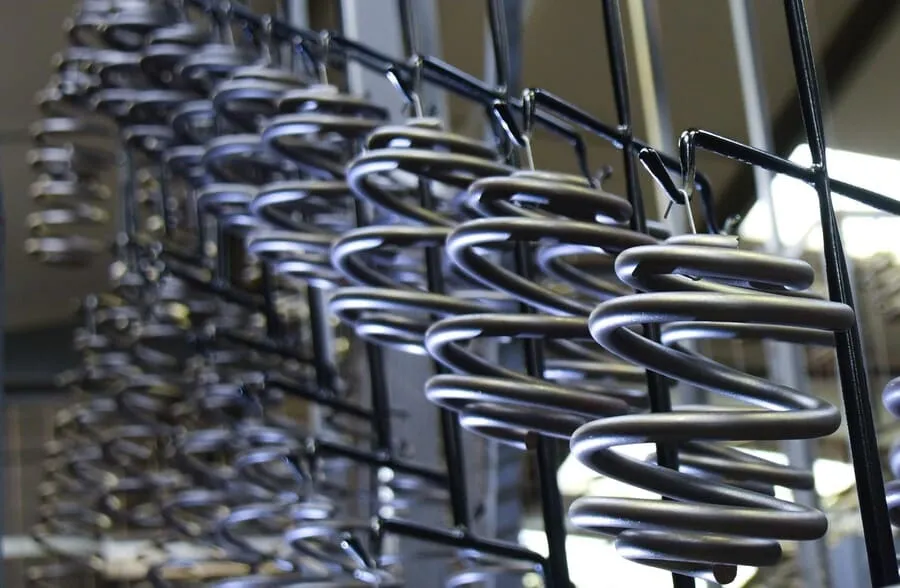 Rows of metal coil springs hanging from a production rack inside Lesjöfors’manufacturing facility