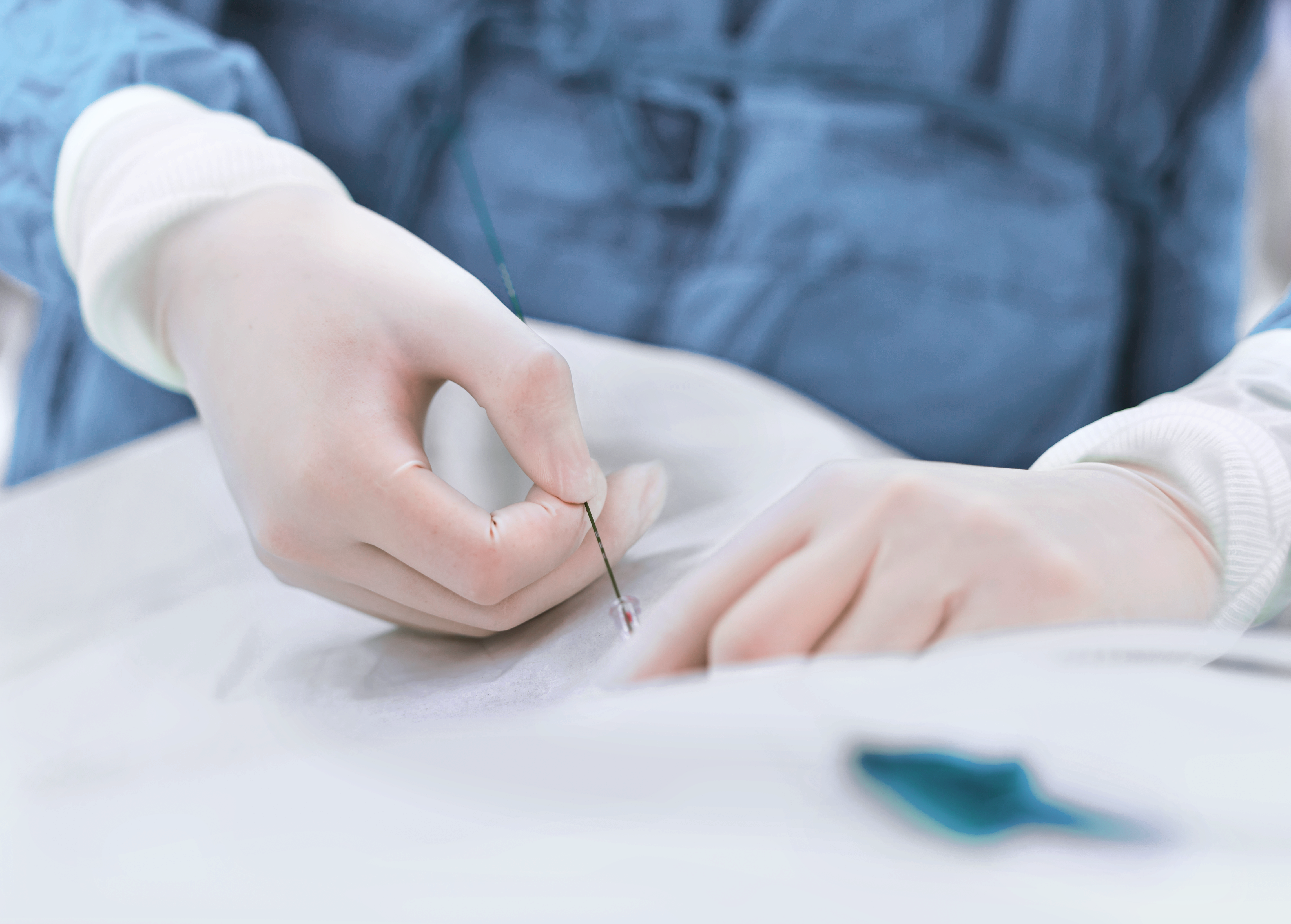 A healthcare professional's gloved hands carefully prepare a needle for an injection.