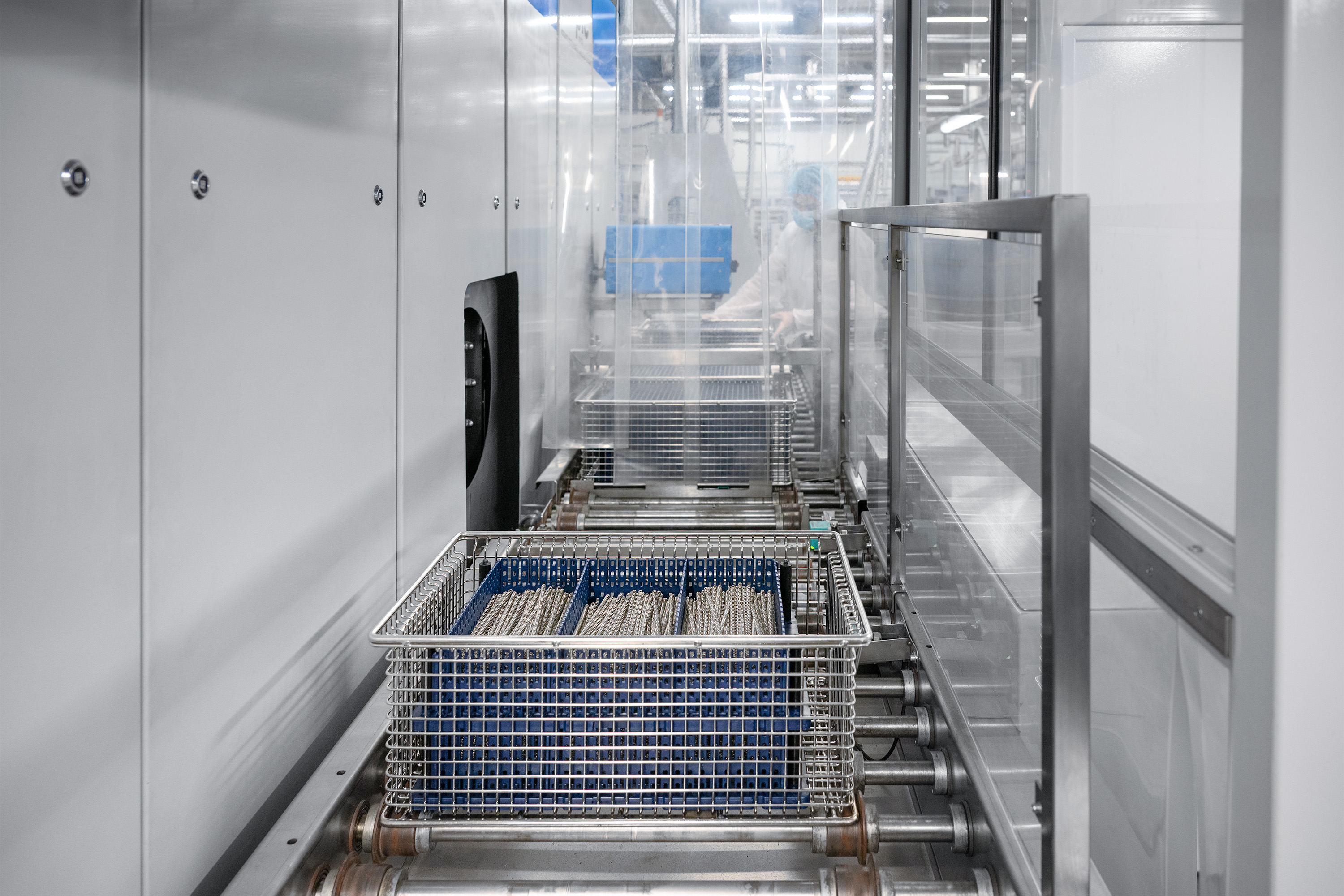 Industrial setting showing a conveyor belt system with sleek, metallic design. The environment is clean and sterile, suggesting a high-tech facility.