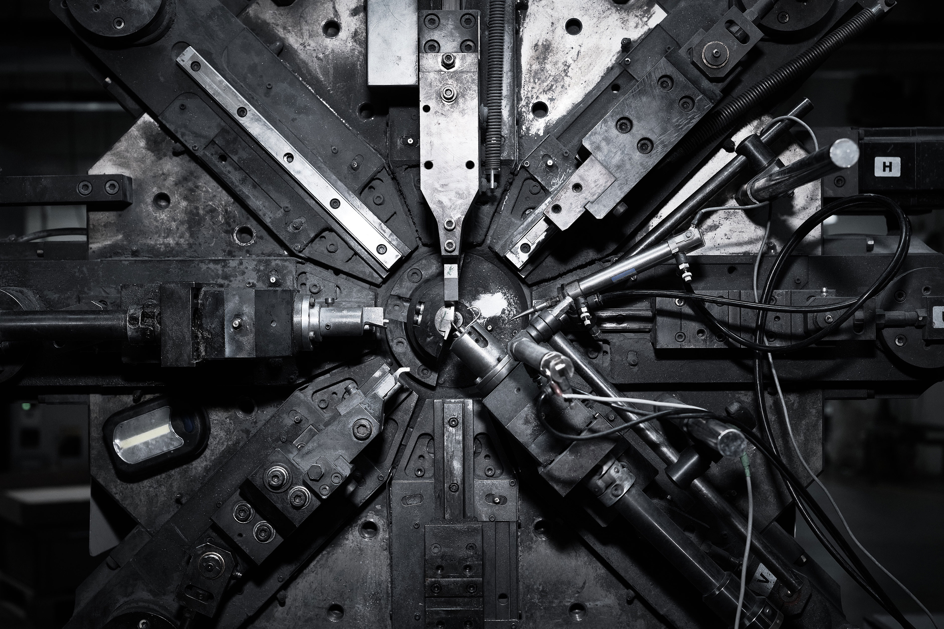 Close-up of an intricate mechanical assembly with multiple metal arms and cables radiating from a central point, conveying a complex, industrial feel.