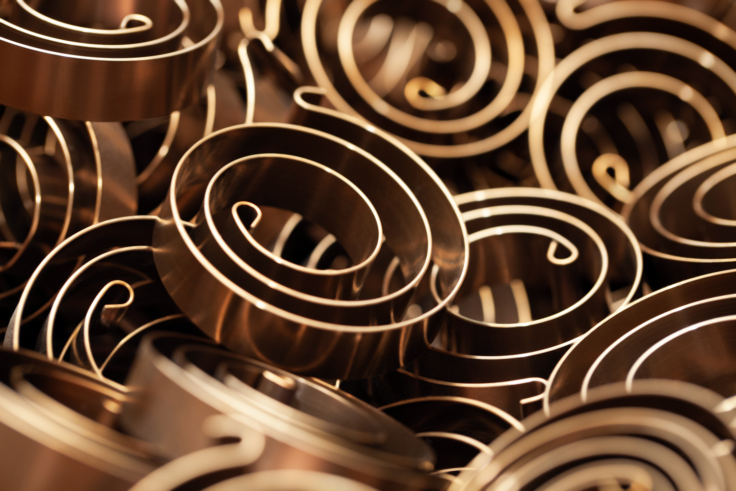 Close-up of numerous spiral torsion springs, creating a pattern of spirals and curves. The image conveys complexity and texture.