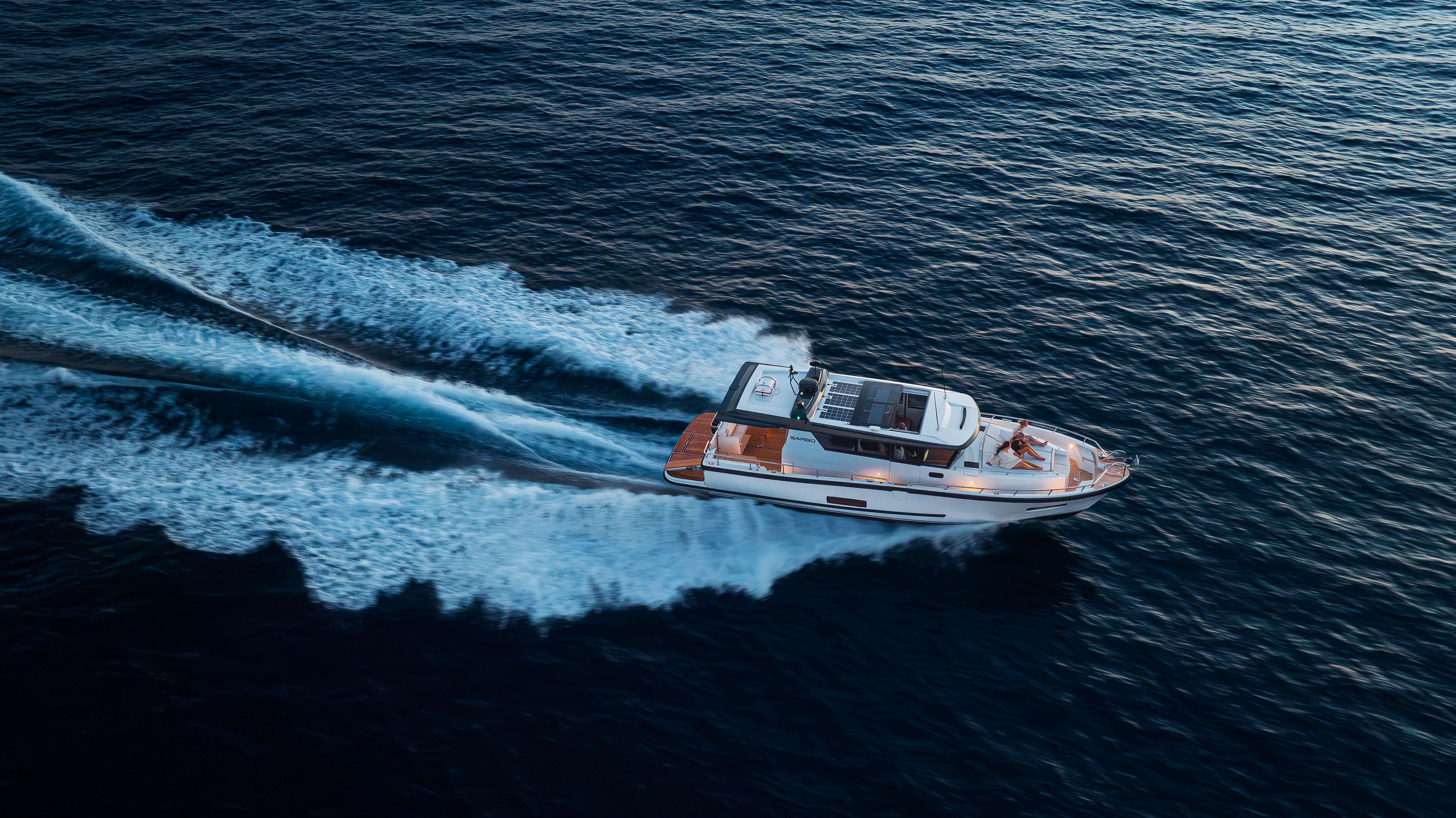 A speedboat cuts through the deep blue ocean, leaving a white wake behind.