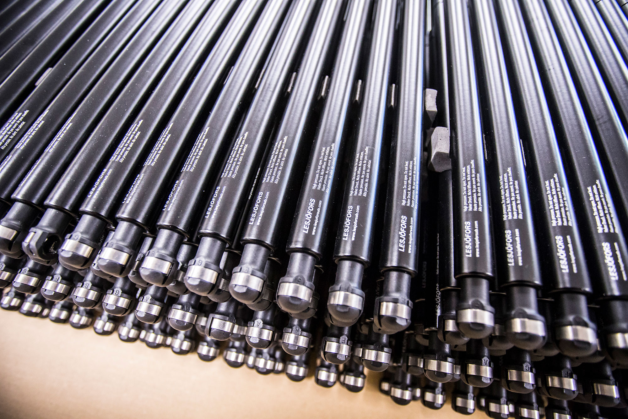 Close-up of multiple black compression gas springs arranged in parallel, extending diagonally across the frame.