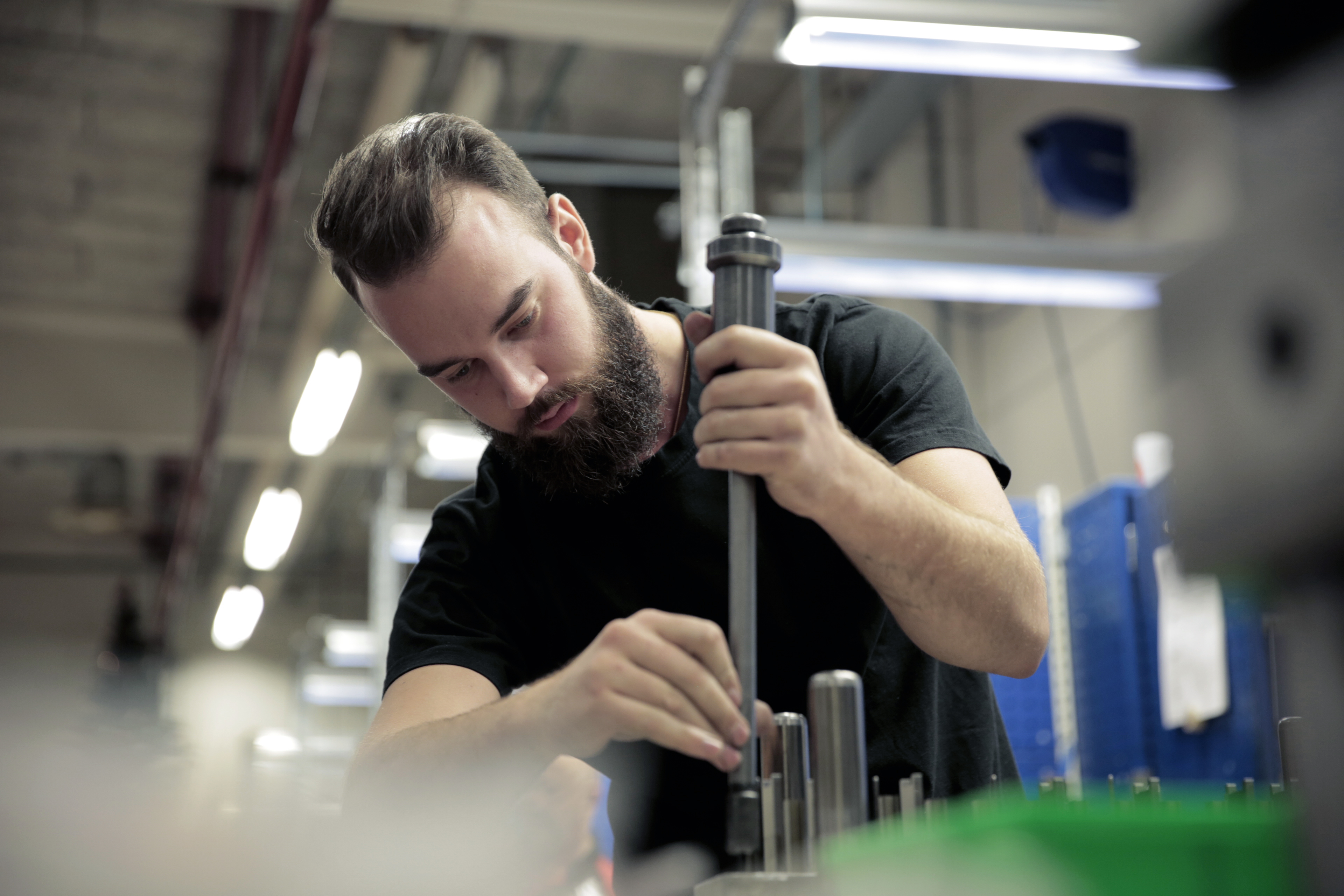 A worker adjusting a metal tool for stamping and pressing in an industrial workshop.