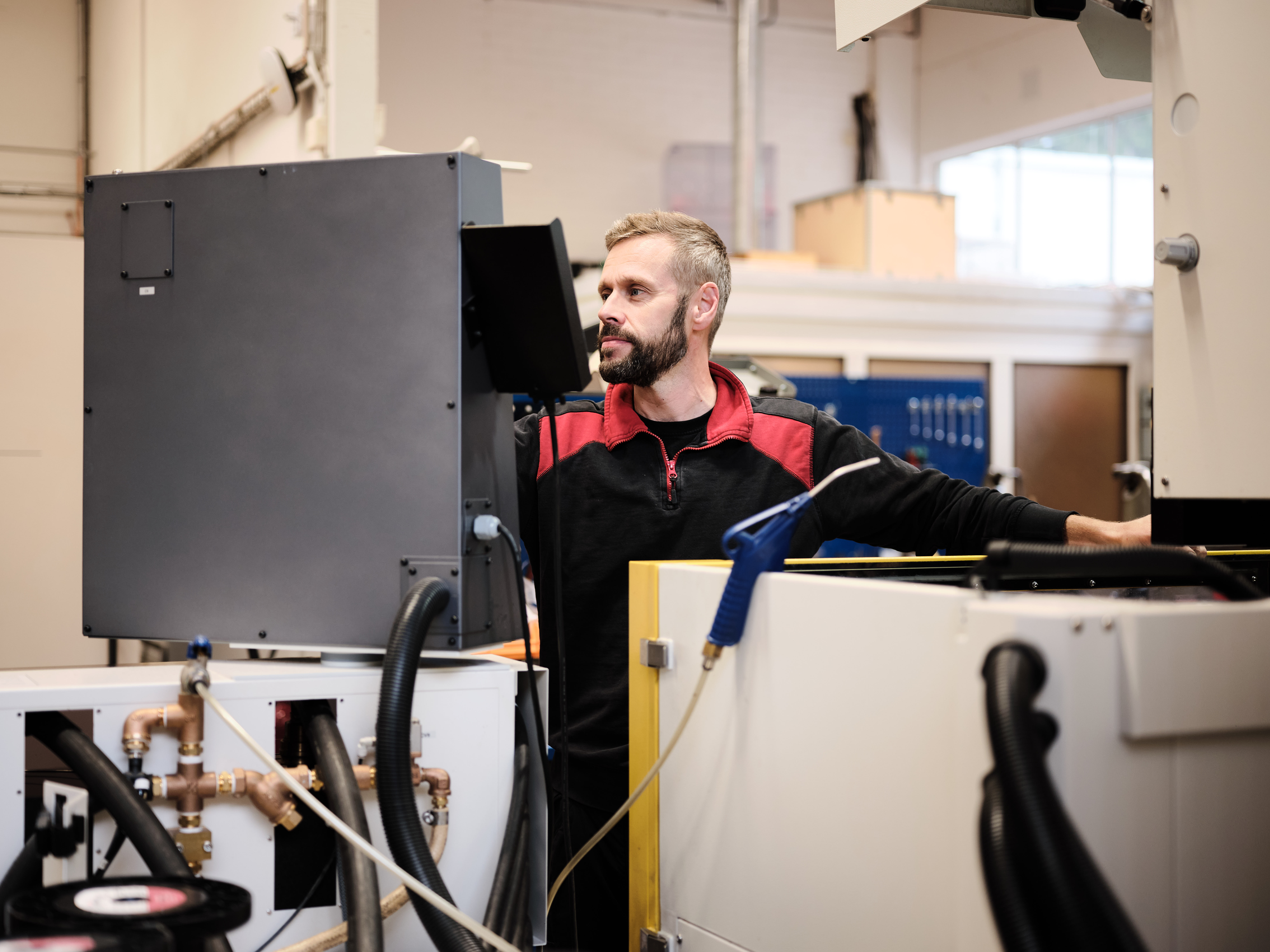 A worker operating industrial machinery and monitoring a control screen in a factory.