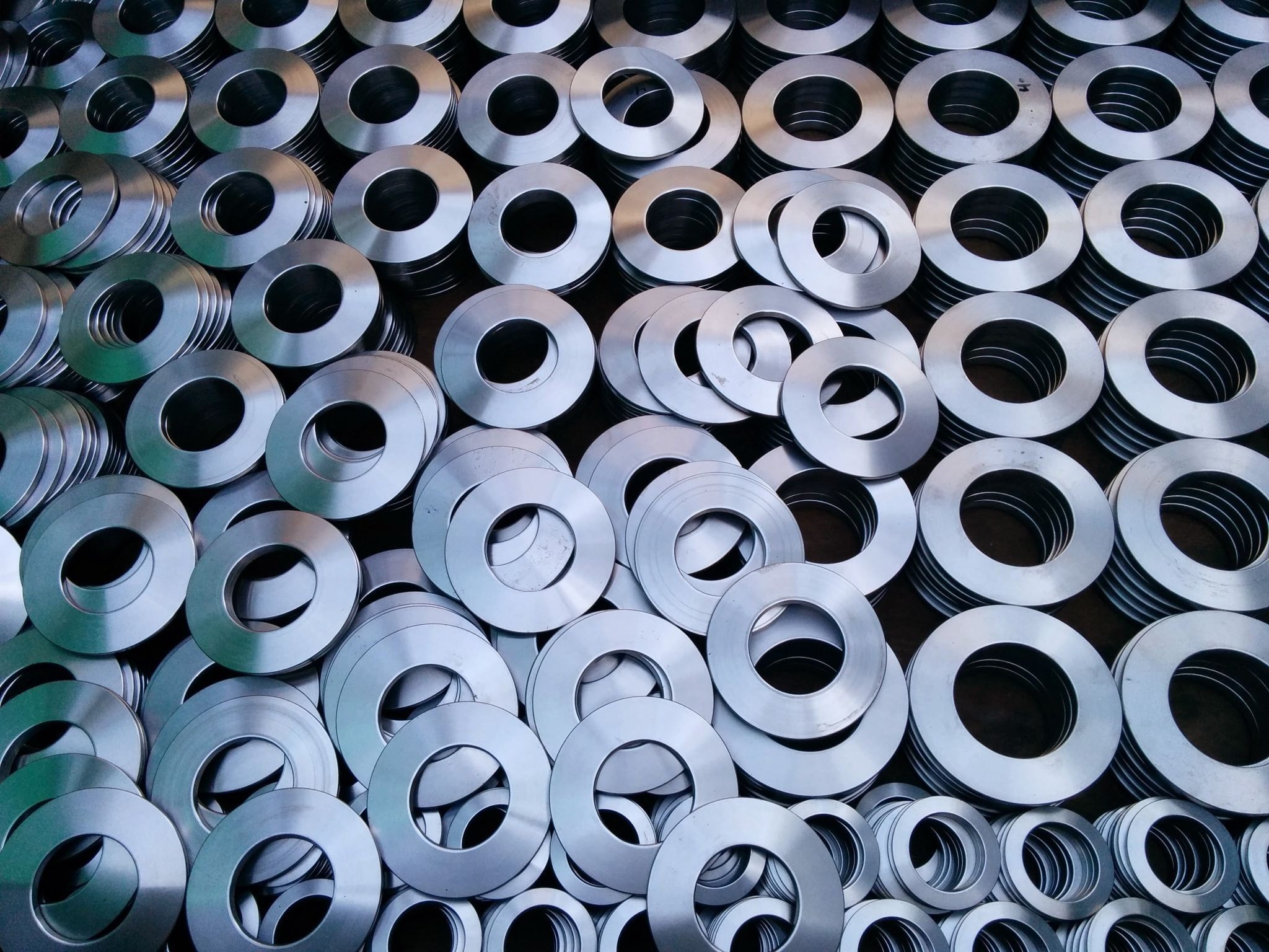 Piles of stainless steel disc springs stacked and arranged in rows.