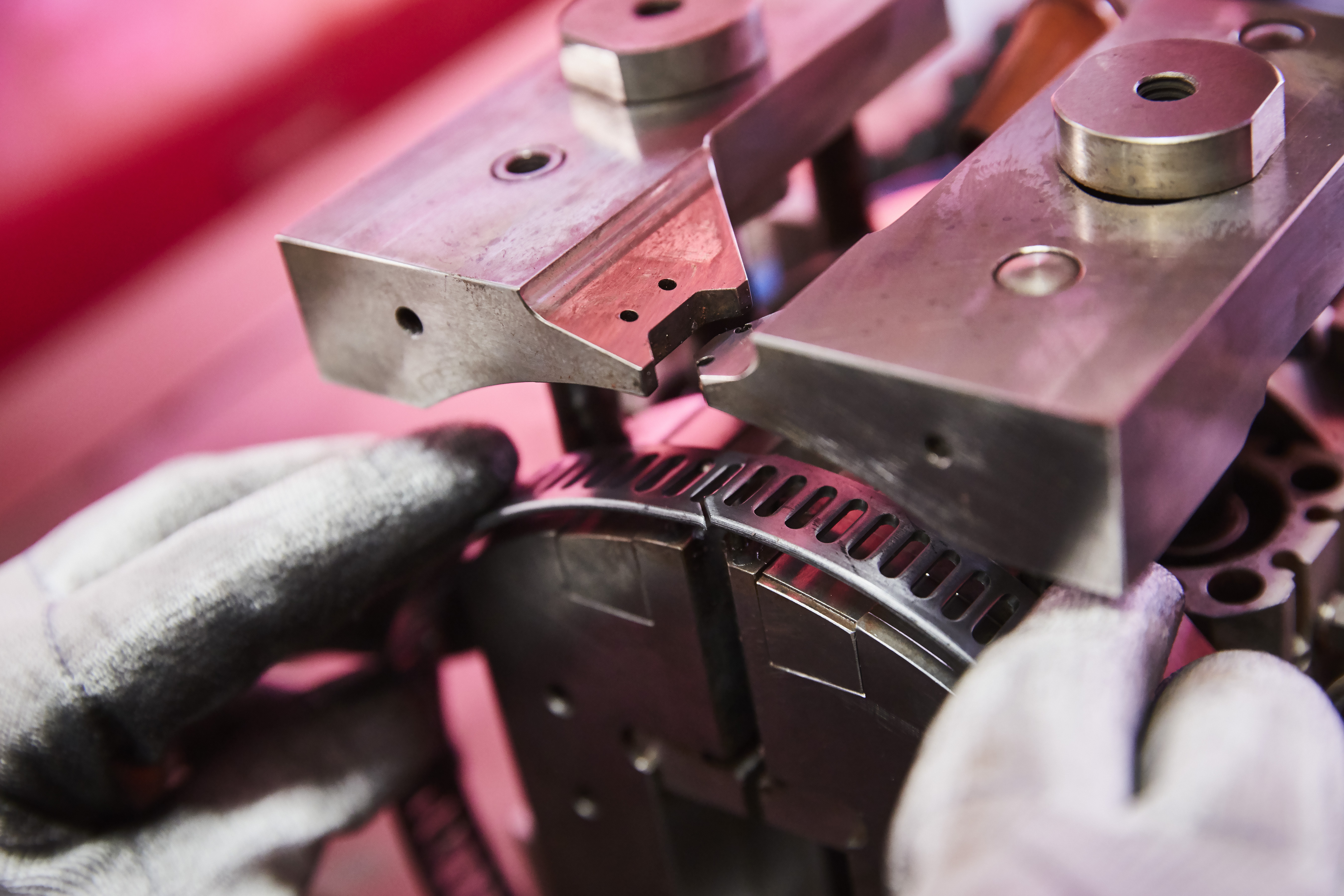 Close-up of a worker operating a metal stamping machine, positioning a circular metal component.