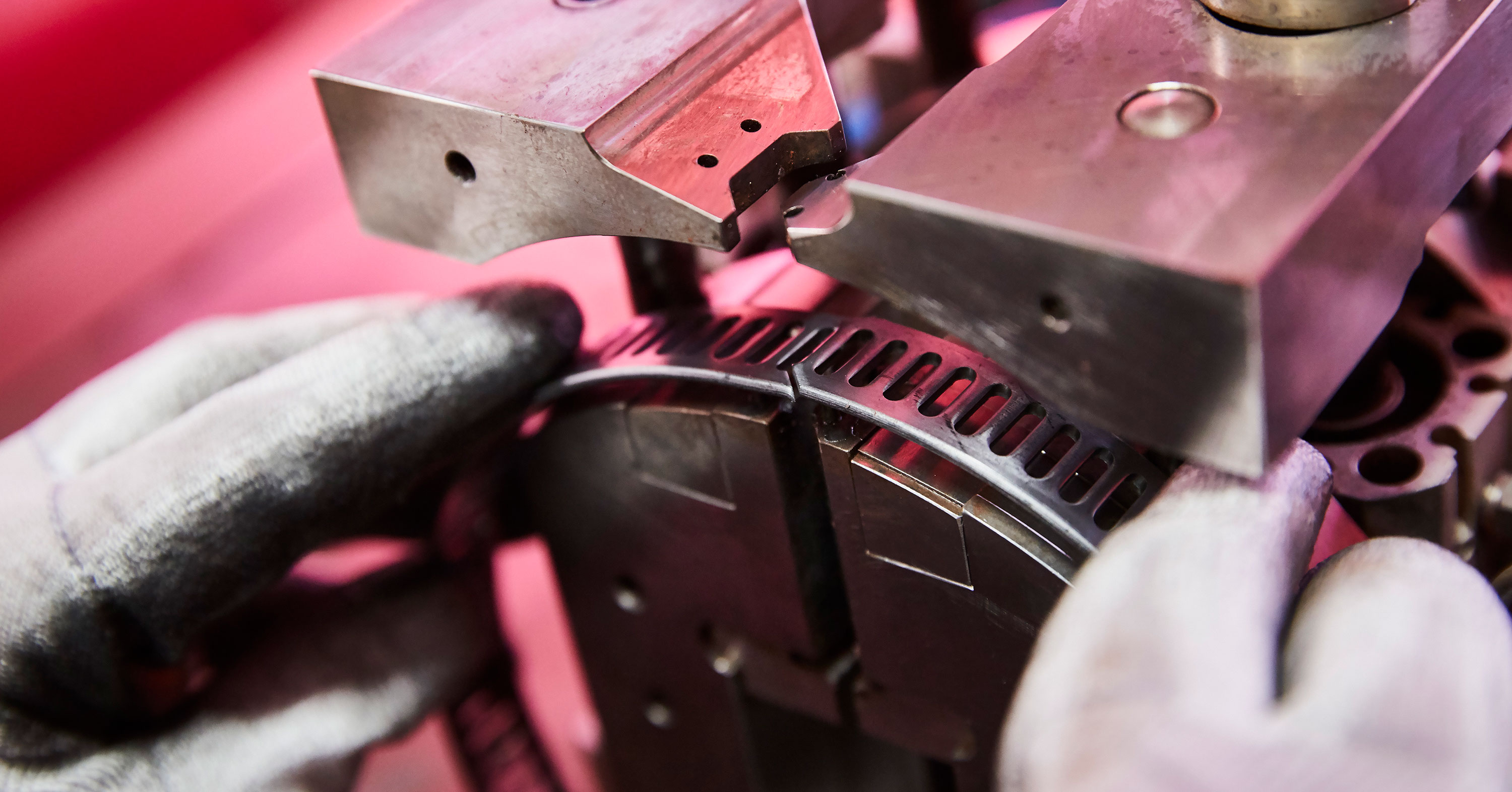 Close-up of a worker operating a metal stamping machine, positioning a circular metal component.