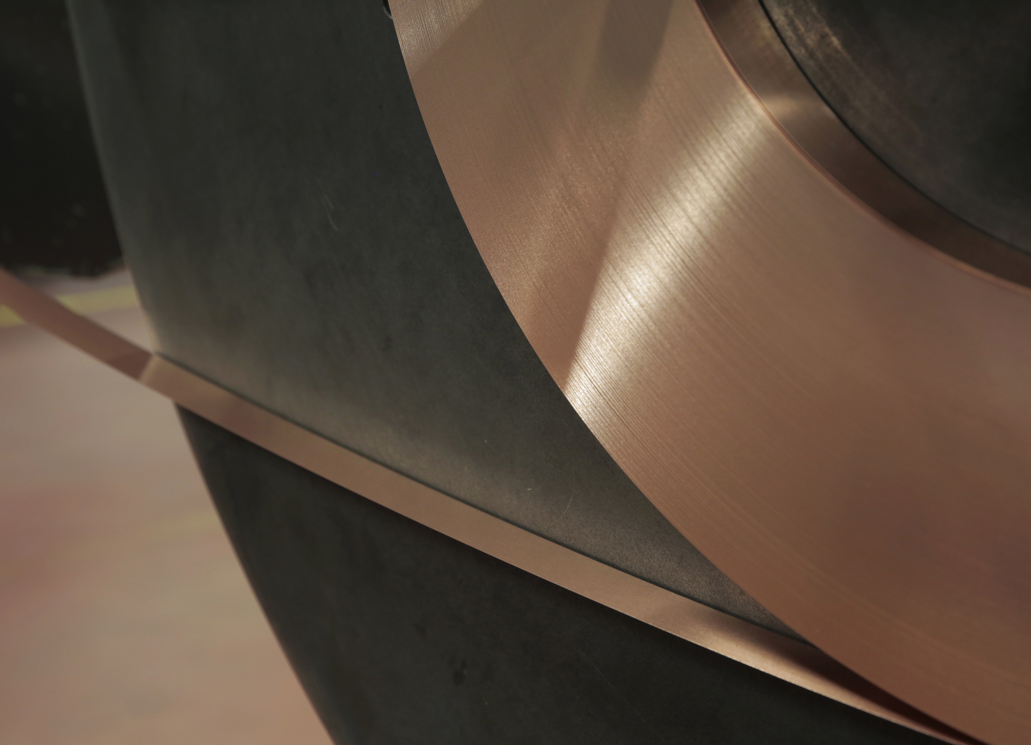 Close-up of a copper coil strip wound around a large spool.